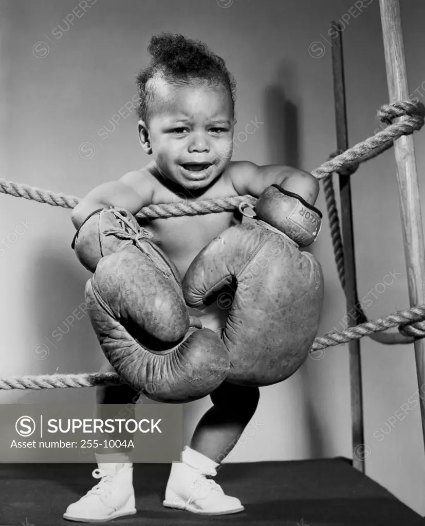 Crying baby wearing boxing gloves