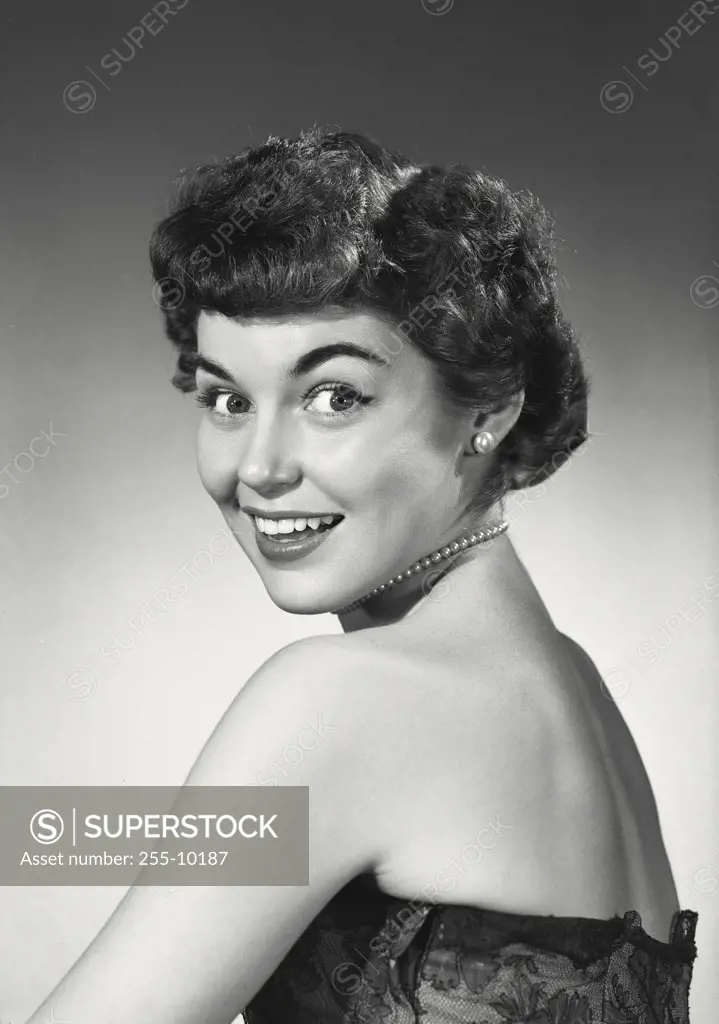 Vintage photograph. Brunette woman with short hair turning back toward viewer smiling