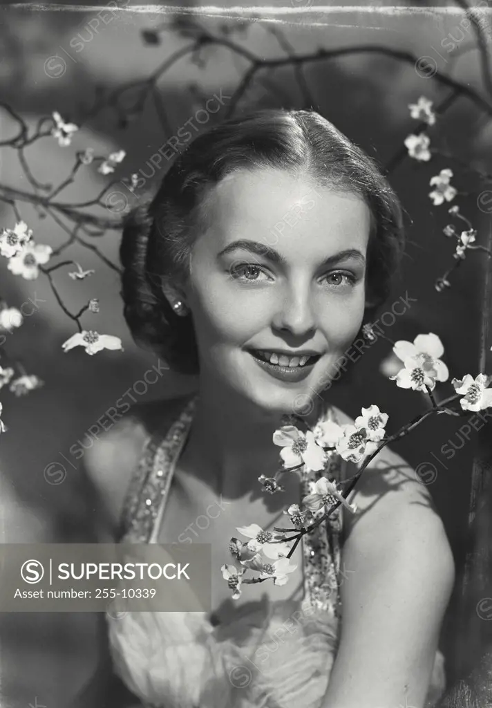 Vintage photograph. Portrait of woman in dress smiling in dogwood branches.