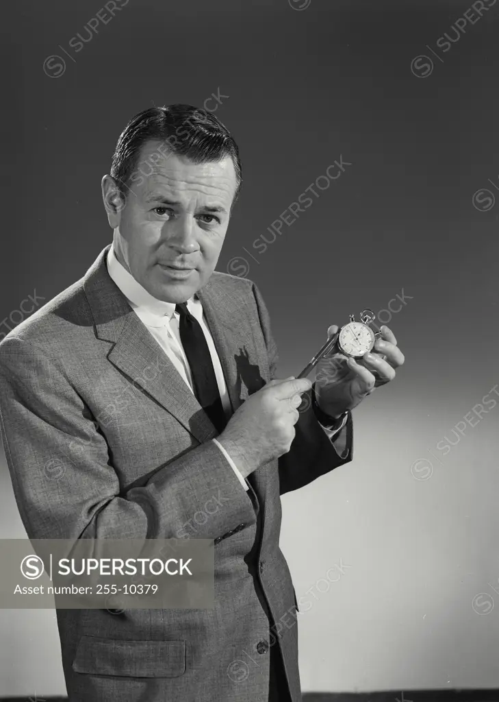 Vintage Photograph. Man in suit holding stopwatch and pen looking at camera