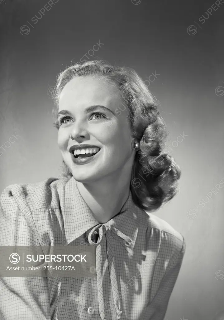 Vintage Photograph. Smiling blonde woman wearing button up blouse with knot tied on collar