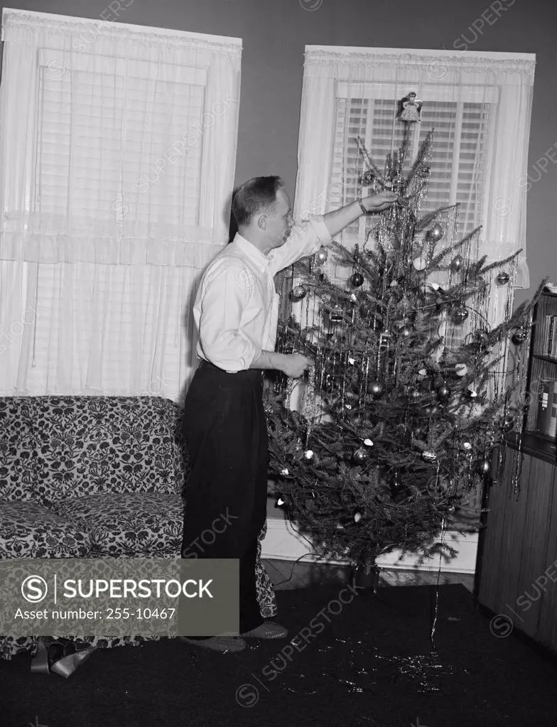 Side profile of a mid adult man decorating a Christmas tree