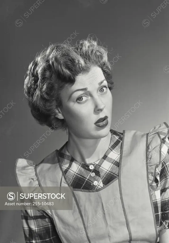 Vintage photograph. Portrait of a young woman in apron with confused expression looking at camera