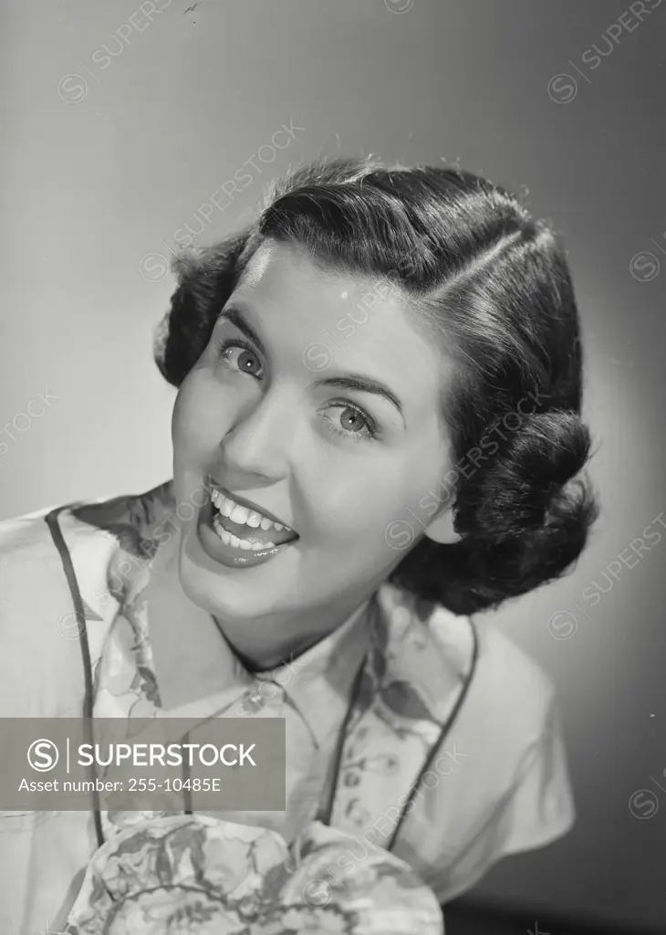 Vintage Photograph. Smiling brunette woman with curled hair wearing apron over blouse with exaggerated happy expression