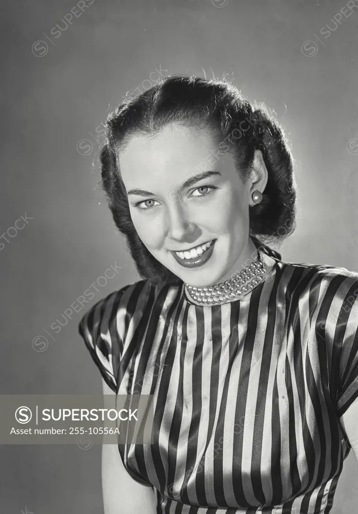 Brunette woman wearing striped silk blouse and beaded necklace smiling