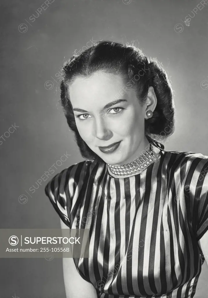 Brunette woman wearing striped silk blouse and beaded necklace