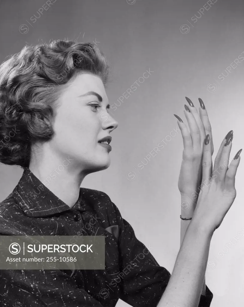 Side profile of a young woman looking at her fingernails