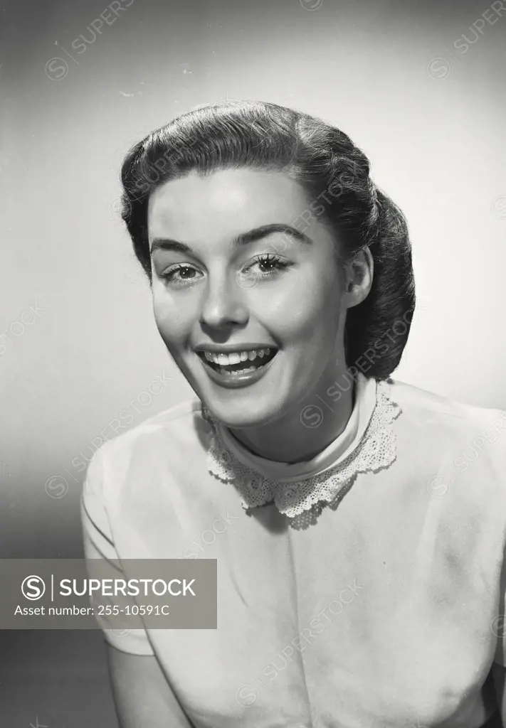 Woman in blouse with lace collar smiling wide at camera