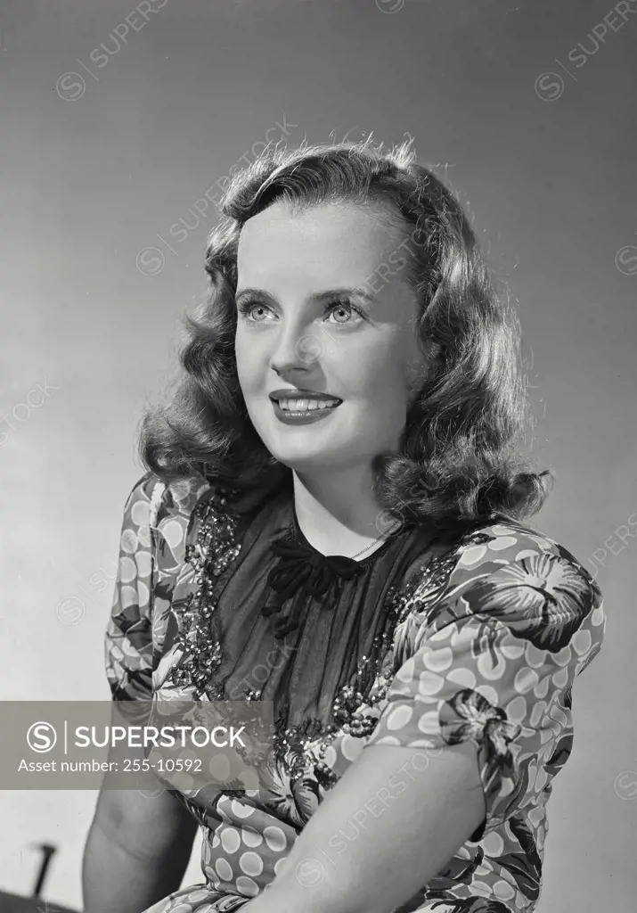 Vintage Photograph. Woman in floral blouse smiling off of camera.