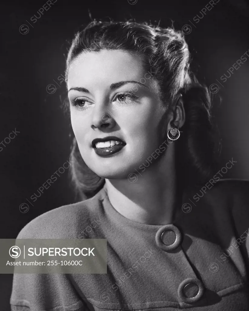 Vintage Photograph. Blonde woman wearing blouse with two large buttons and heart earrings turned and looking off camera