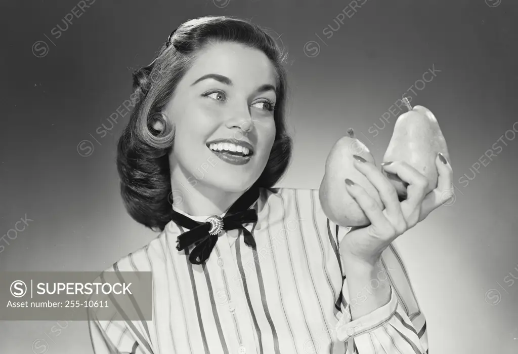 Vintage Photograph. Woman in striped button shirt smiling wide and holding a pair of pears