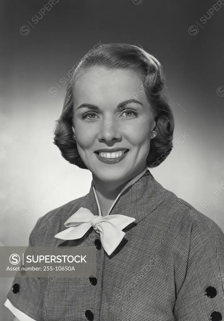 Vintage photograph. Woman in button blouse with bow smiling at camera