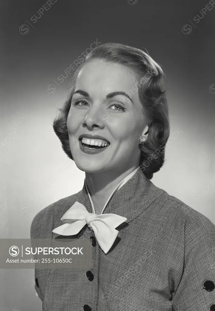 Vintage photograph. Woman in button blouse with bow smiling at camera