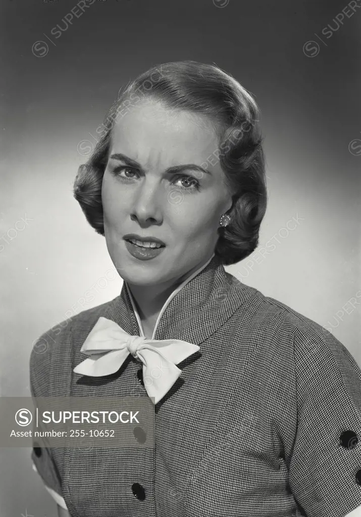 Vintage photograph. Woman in button blouse with bow looking confused at camera