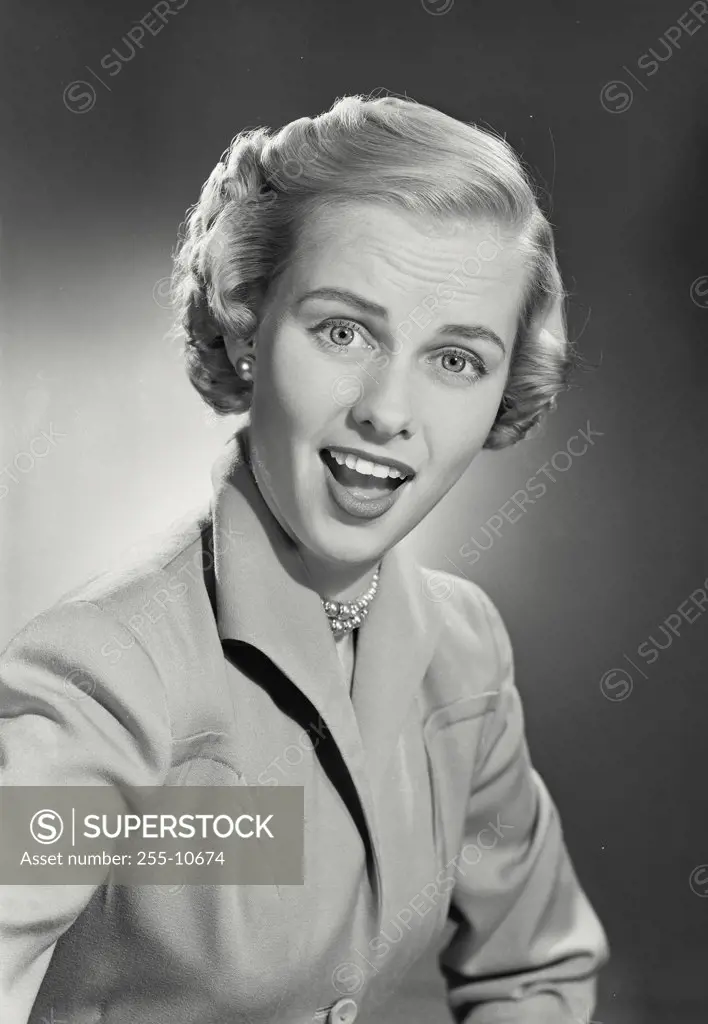 Vintage photograph. Woman with short hair in coat smiling with mouth wide at camera.