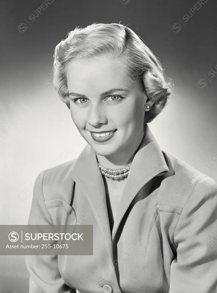 Vintage photograph. Woman with short hair in coat smiling at camera.