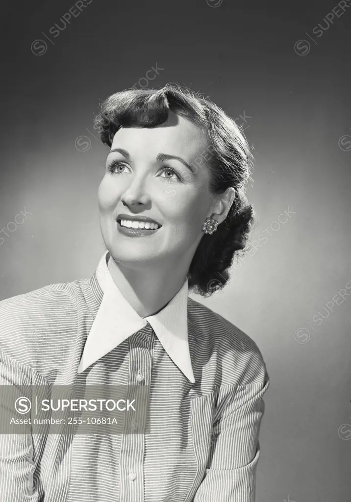 Vintage photograph. Brunette woman wearing striped blouse with white collar looking up and smiling