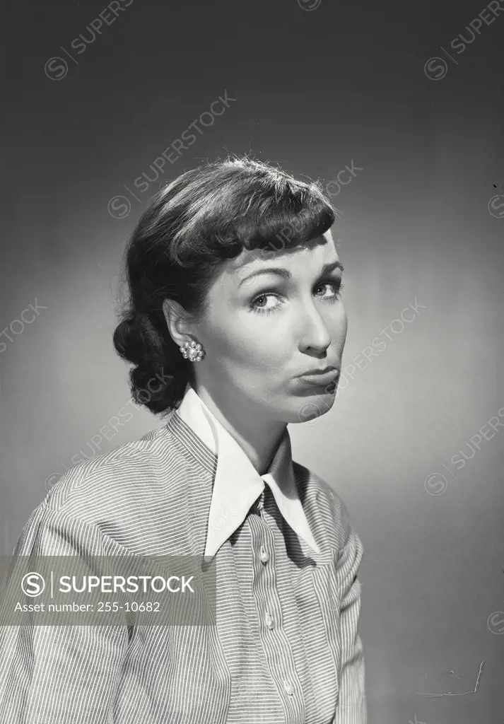 Vintage photograph. Brunette woman wearing striped blouse with white collar frowning