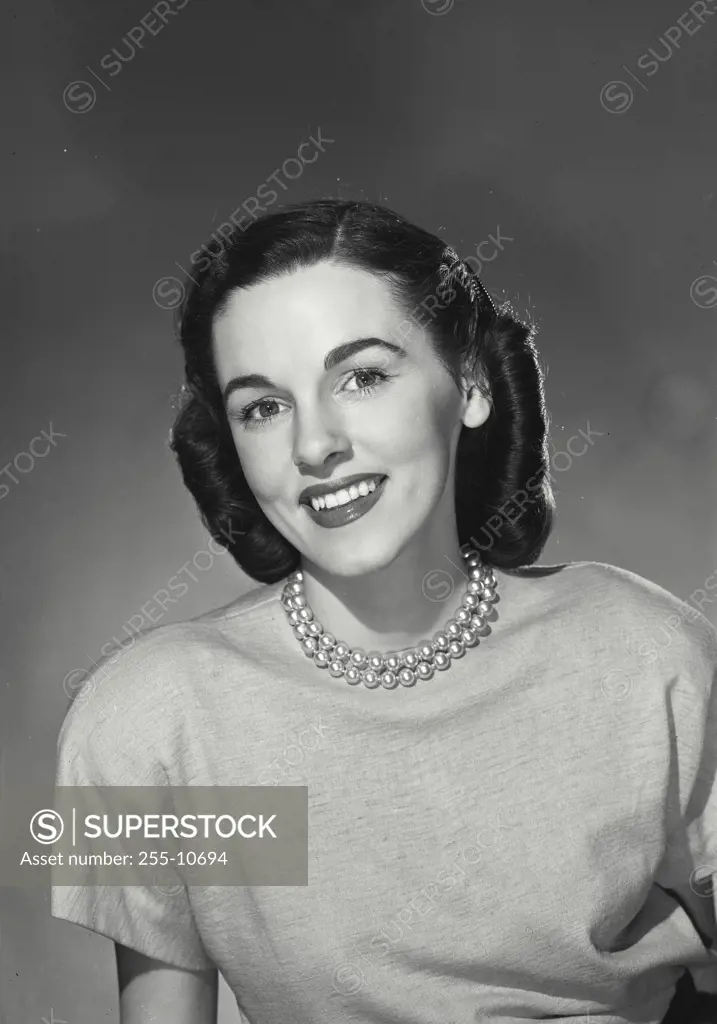 Vintage Photograph. Smiling brunette woman with curled hair wearing pearl necklace