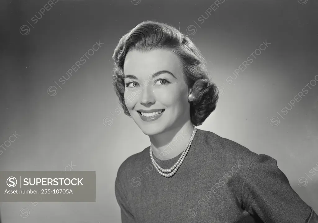Vintage Photograph. Woman in sweater and pearl necklace smiling off camera