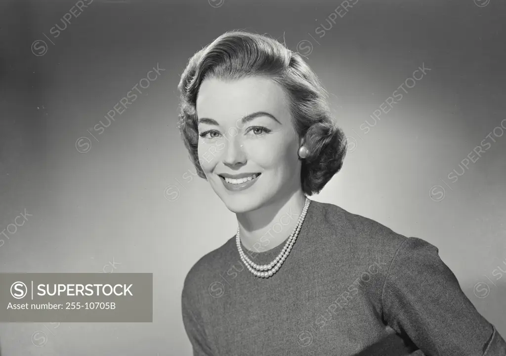 Vintage Photograph. Woman in sweater and pearl necklace smiling wide at camera