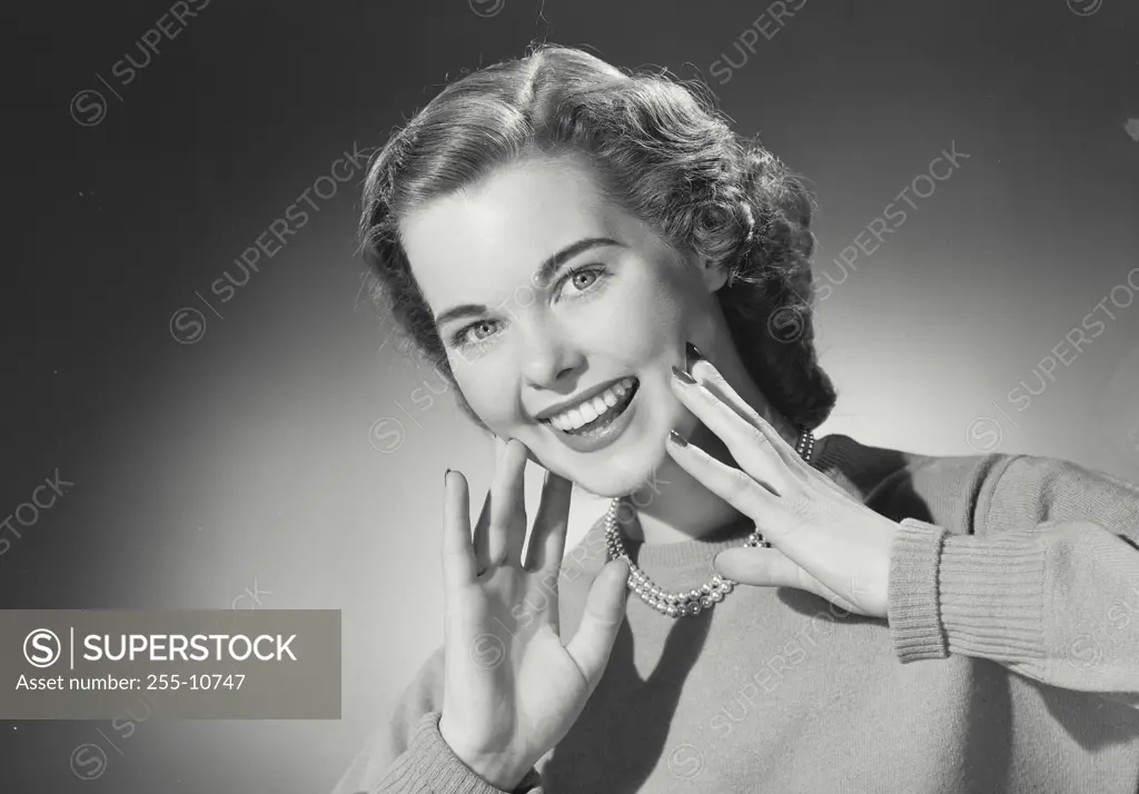 Vintage Photograph. Woman in sweater and pearls smiling with hands on cheeks