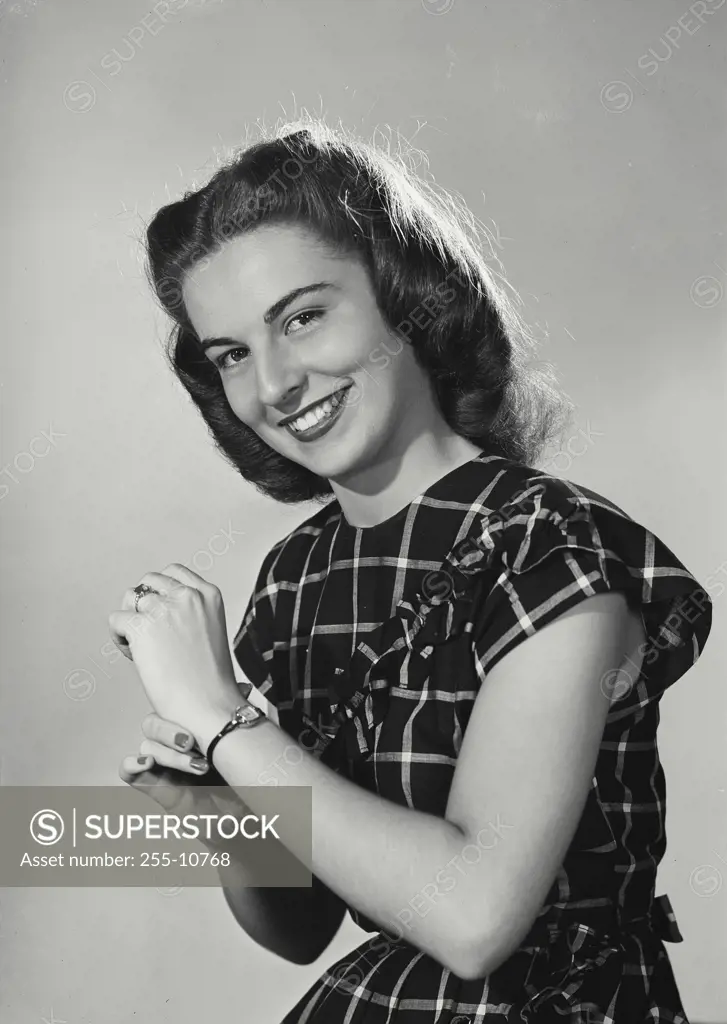 Vintage Photograph. Smiling brunette woman wearing square patterned dress showcasing bracelet on left wrist