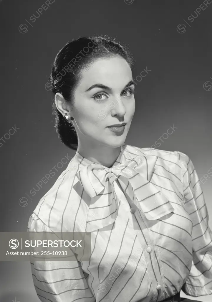 Vintage Photograph. Woman in button shirt and bowtie smirking at camera