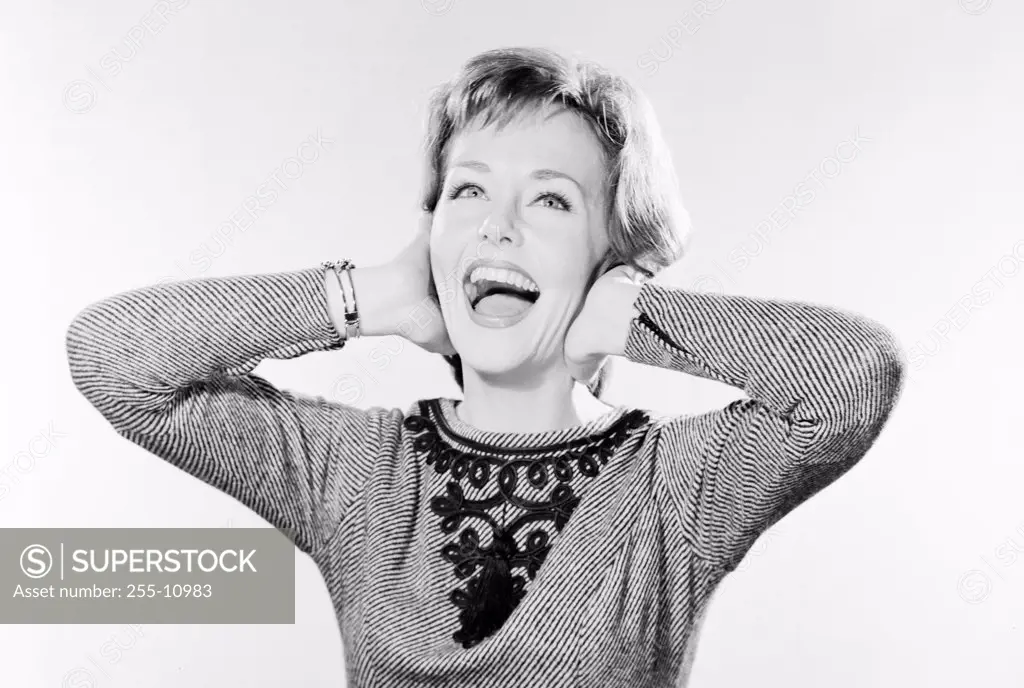 Close-up of a young woman laughing with her hands on her ears