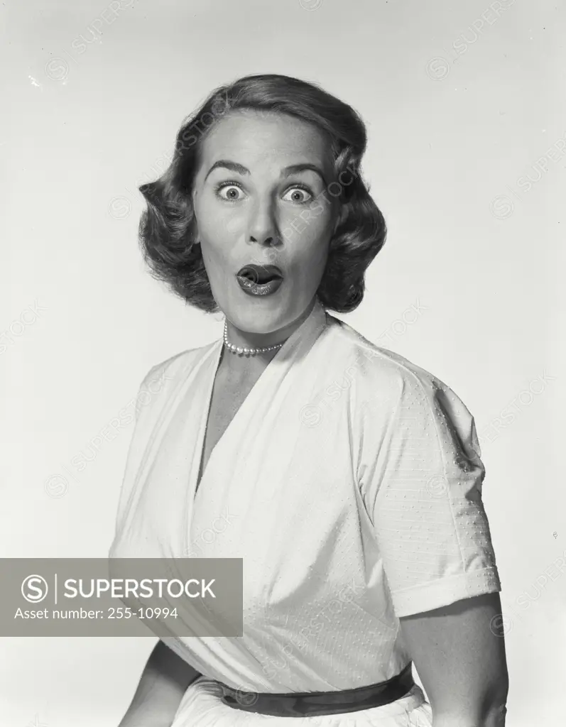 Vintage Photograph. Young woman wearing white dress looking at camera making surprised expression