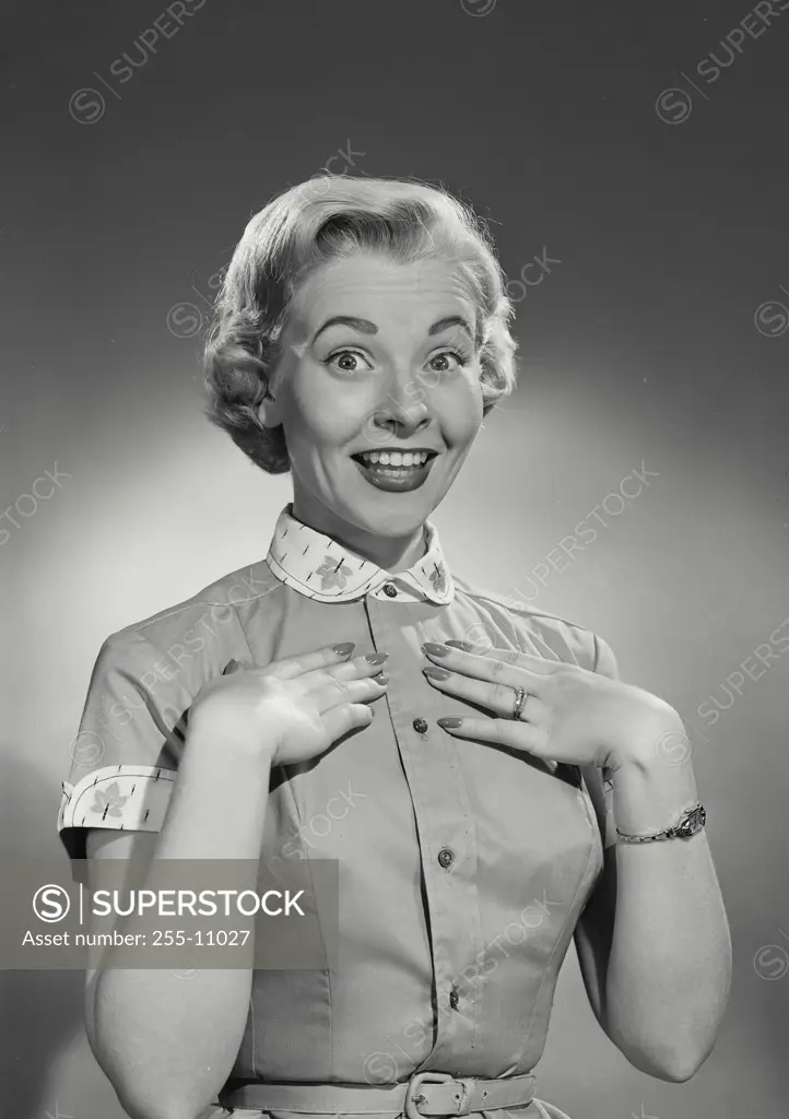 Vintage Photograph. Woman in button blouse smiling with hands on chest.