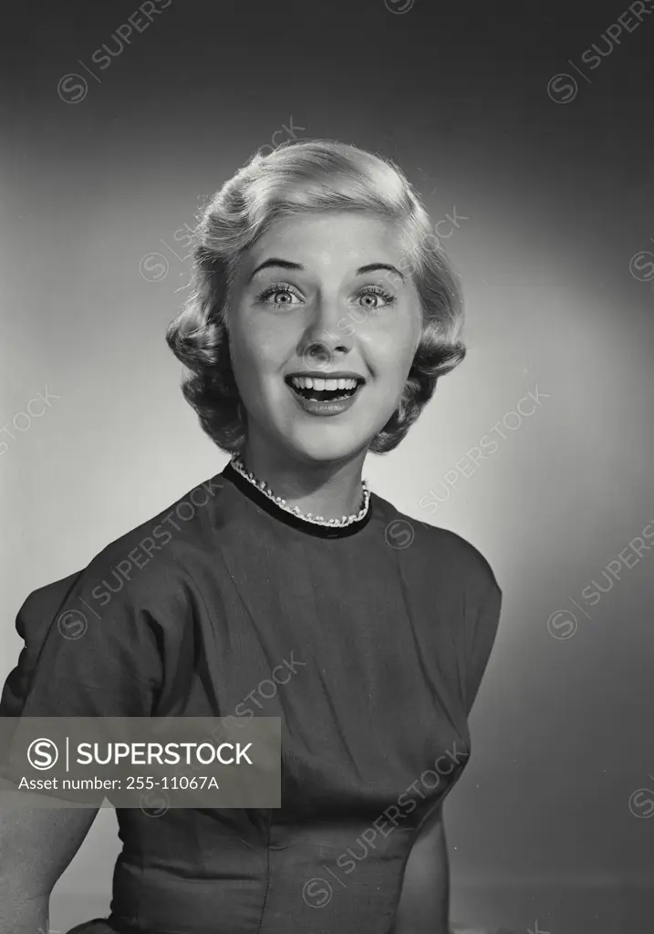 Vintage Photograph. Smiling young woman with short blonde hair wearing high collared blouse with excited expression