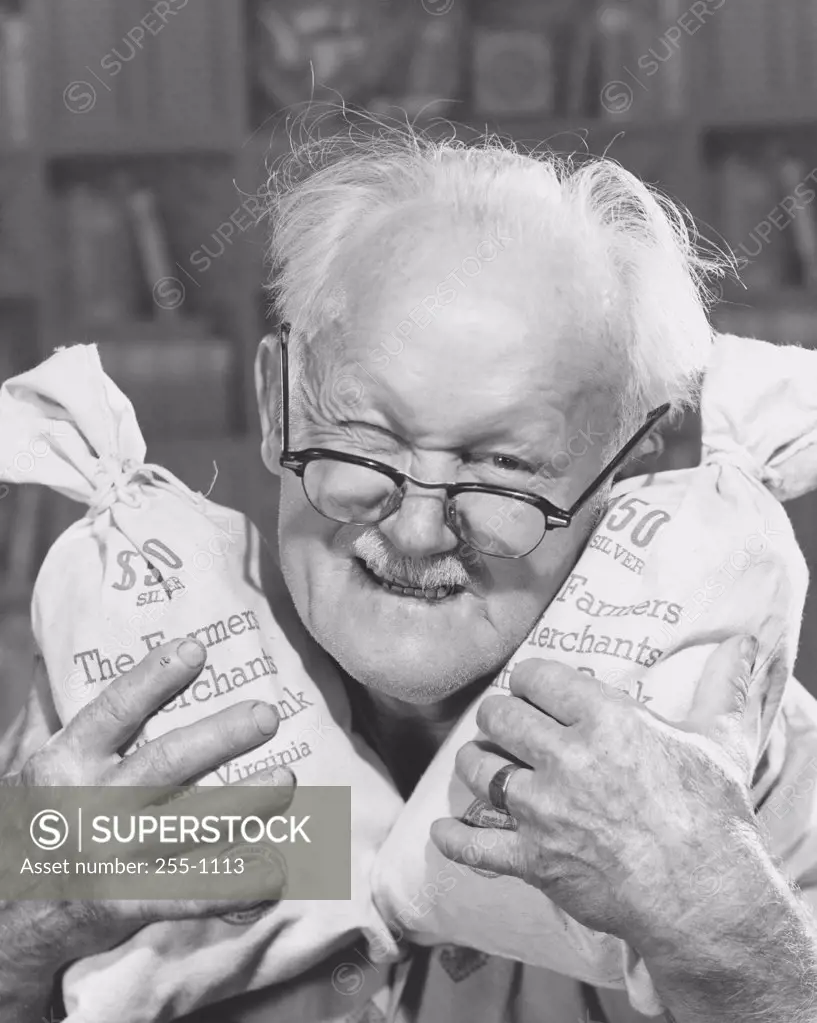 Portrait of a senior man holding two bags of money