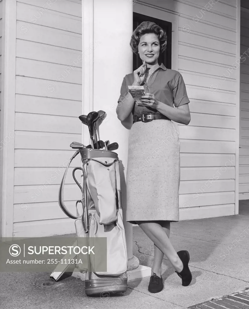 Mid adult woman leaning against a column near a golf bag