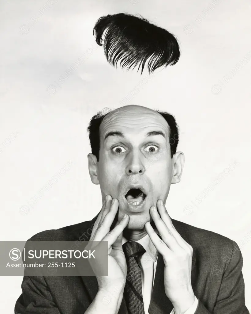 Toupe flying off of a surprised businessman's head