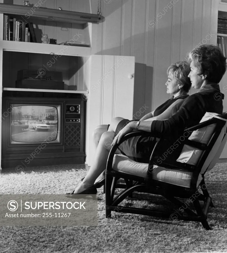 Side profile of two mature women watching television