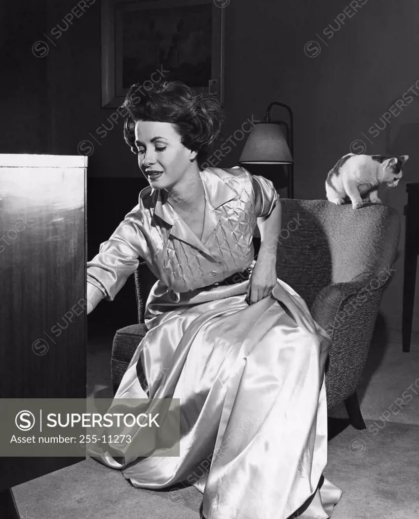 Mid adult woman adjusting a television