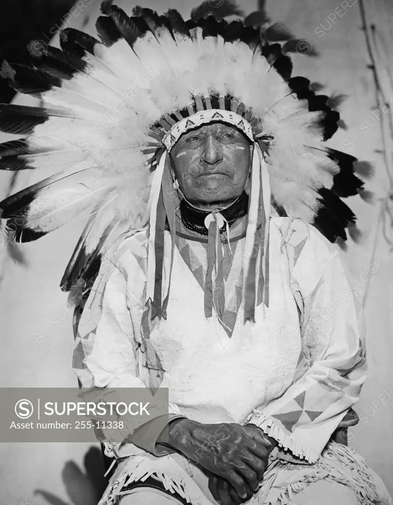 American Horse sitting and wearing a headdress