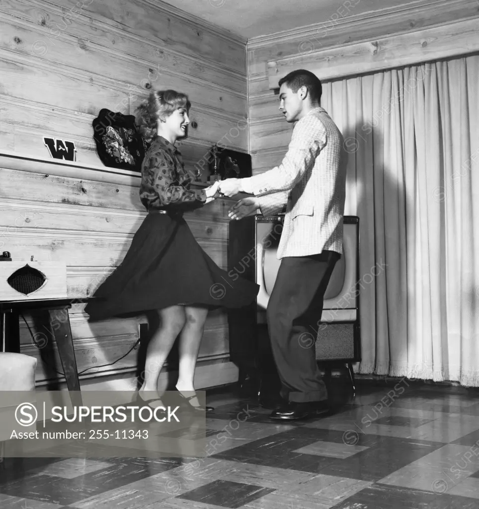 Side profile of a young couple dancing in a living room