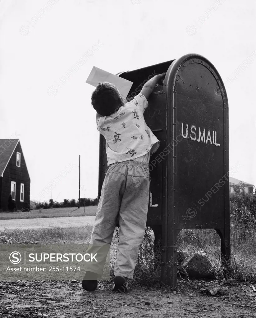 Rear view of a boy dropping mail in a mailbox