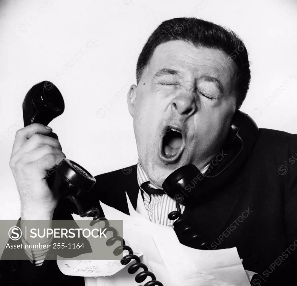 Close-up of a businessman yawning on the telephone