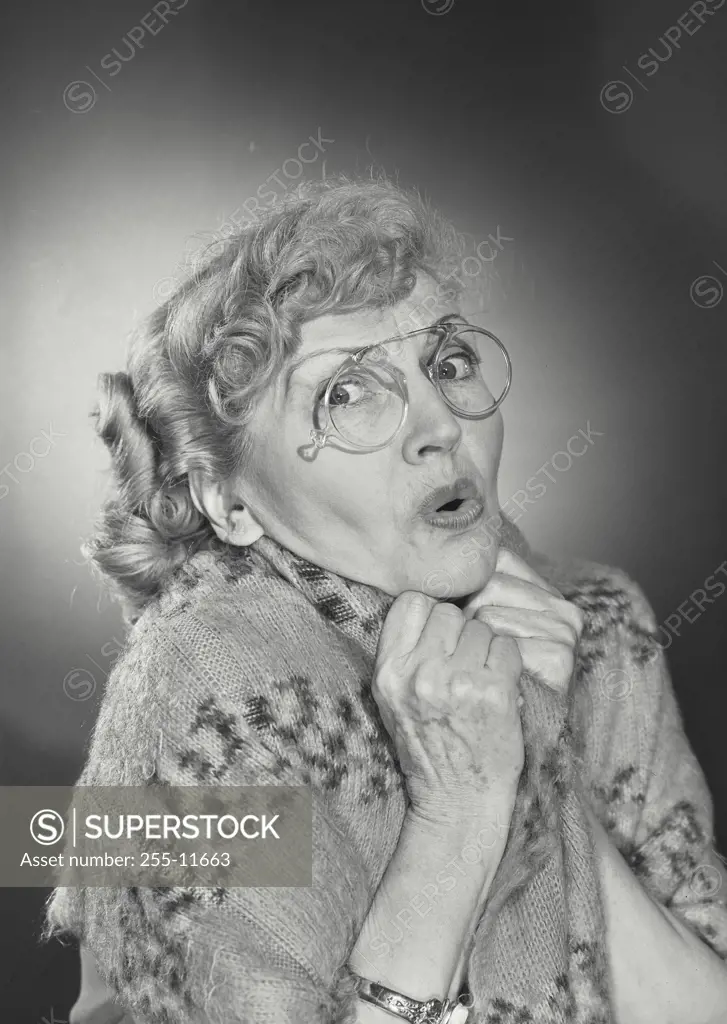 Vintage Photograph. Older woman wearing glasses and huddled in shawl looking frightened