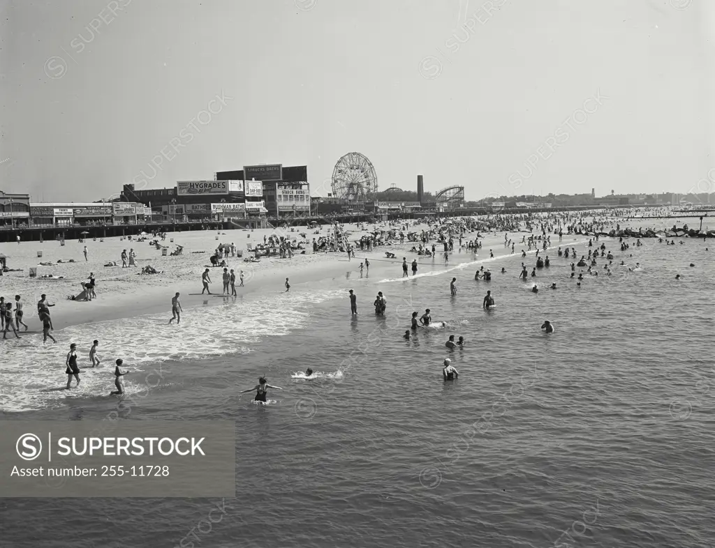 Vintage Photograph. People at the beach at Coney Island with rides in background, New York