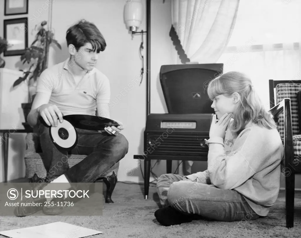 Teenage girl and boy listening to music in home