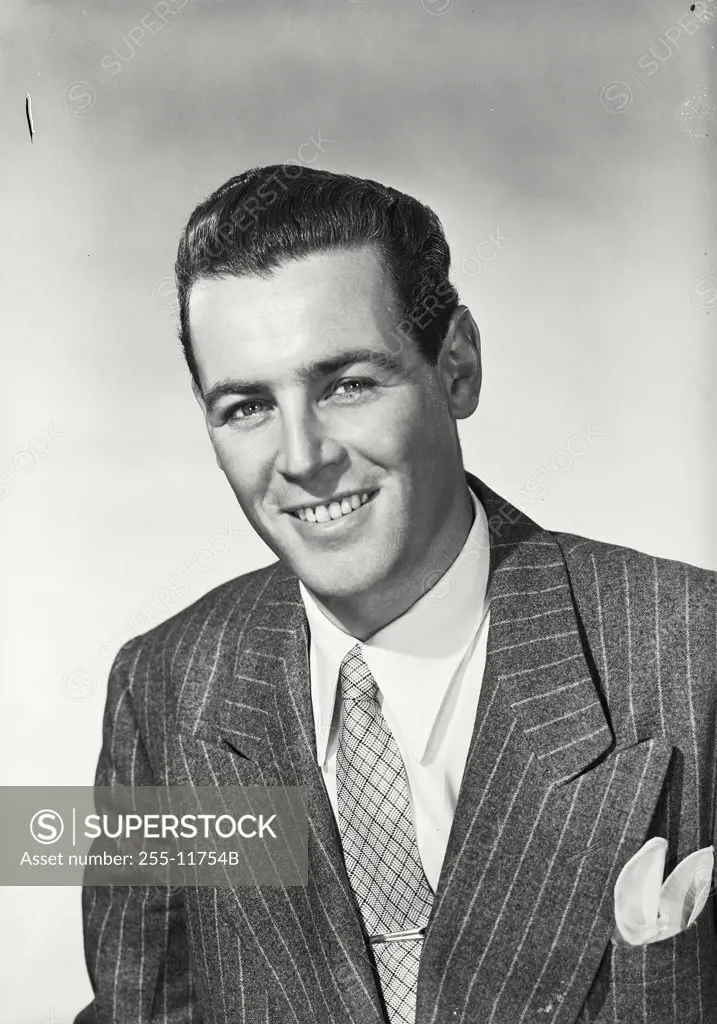 Businessman with dark hair in suit and tie smiling