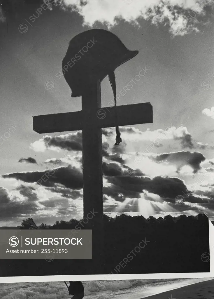 Vintage photograph. Low angle view of a helmet on cross with clouds in background