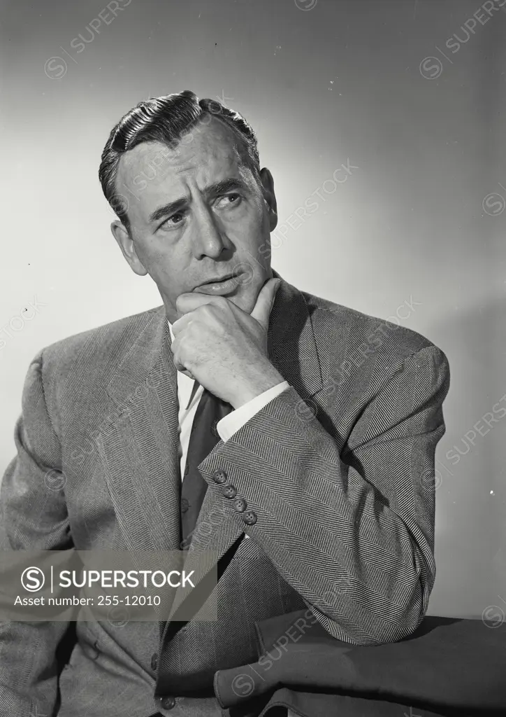 Vintage Photograph. Man wearing suit and tie resting chin in hand looking off camera with concerned expression