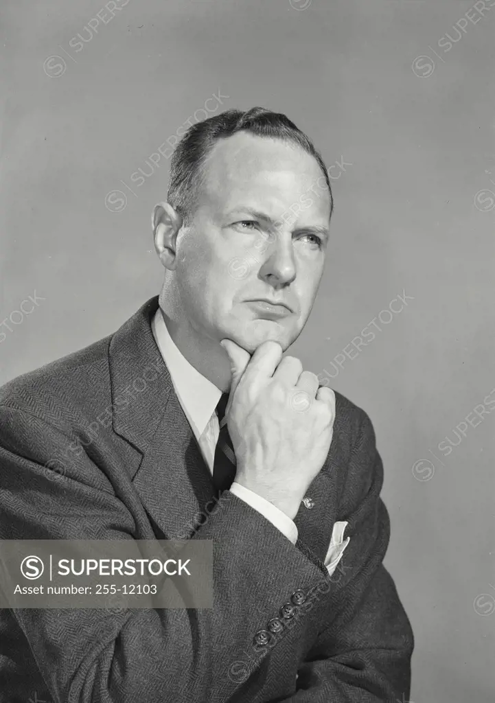 Vintage Photograph. Businessman in suit holding hand to chin in contemplative expression
