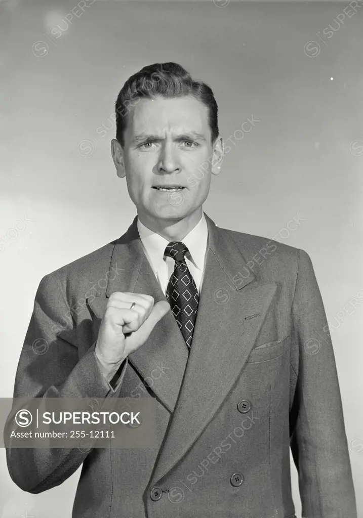 Vintage Photograph. Businessman in suit holding up hand with thumb pointed at chest while making aggressive expression