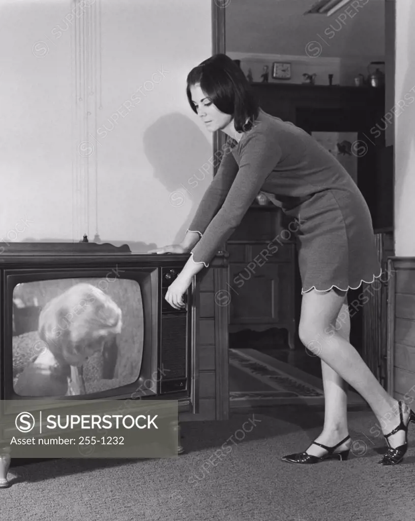Side profile of a young woman changing channels of a television